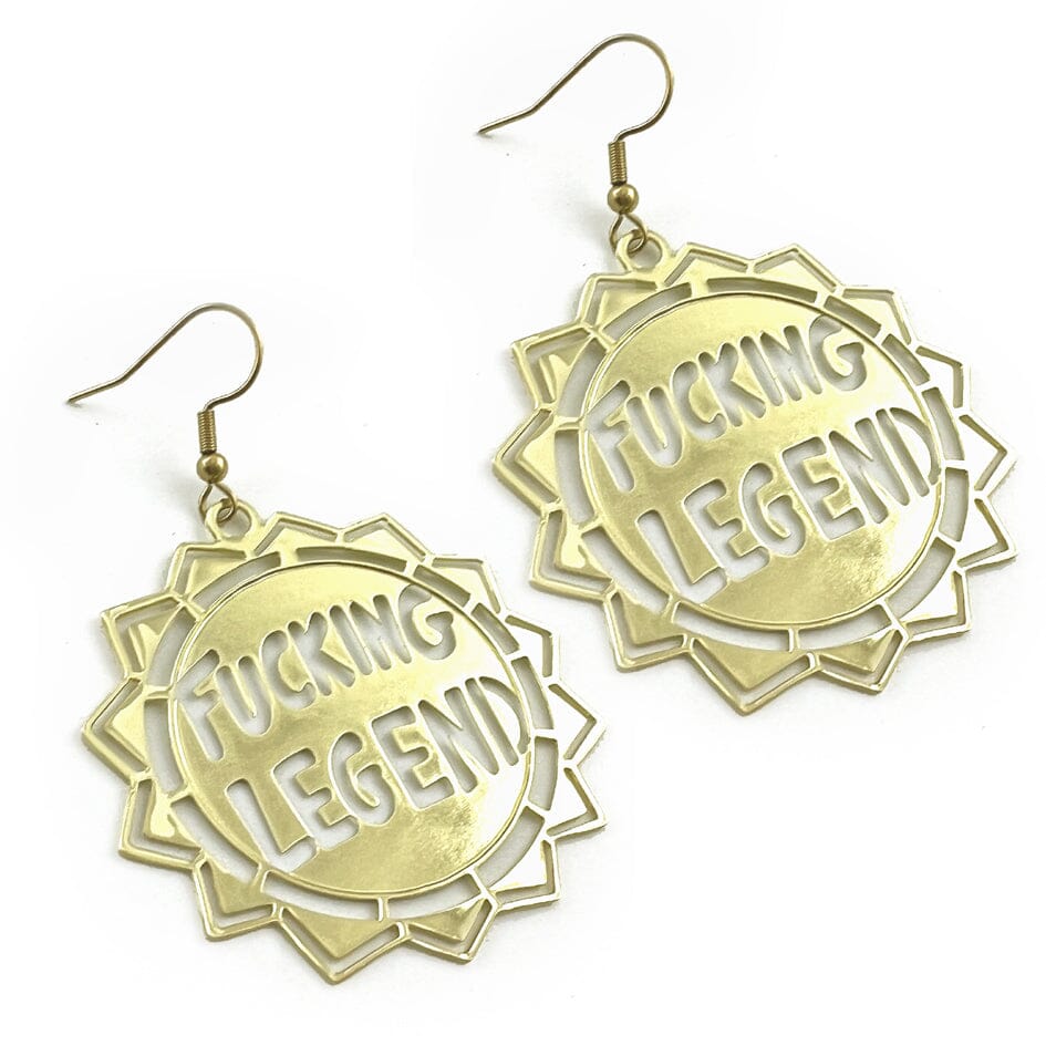 A pair of dangle brass earrings displayed on a white background. The earrings read Fucking Legend.