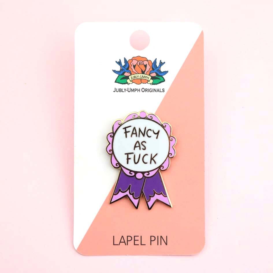 A hard enamel lapel pin on a Jubly-Umph backing card. The pin is in the shape of a pink and purple ribbon award and reads Fancy As Fuck.