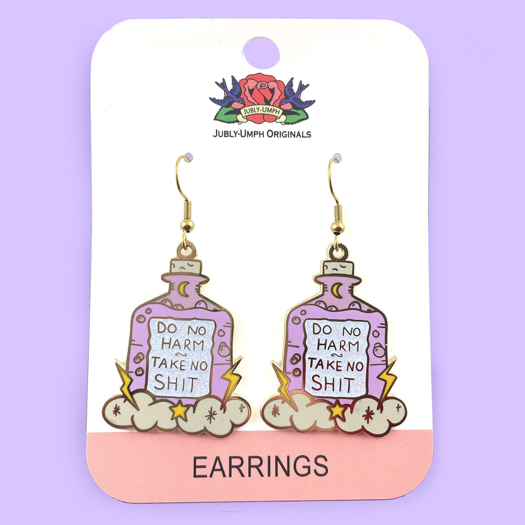 A pair of dangle earrings displayed on on Jubly-Umph cardstock. Displayed on purple background. The earrings are purple and in the shape of a bottle with clouds and lightning bolts. The earrings read Do No Harm Take No Shit.