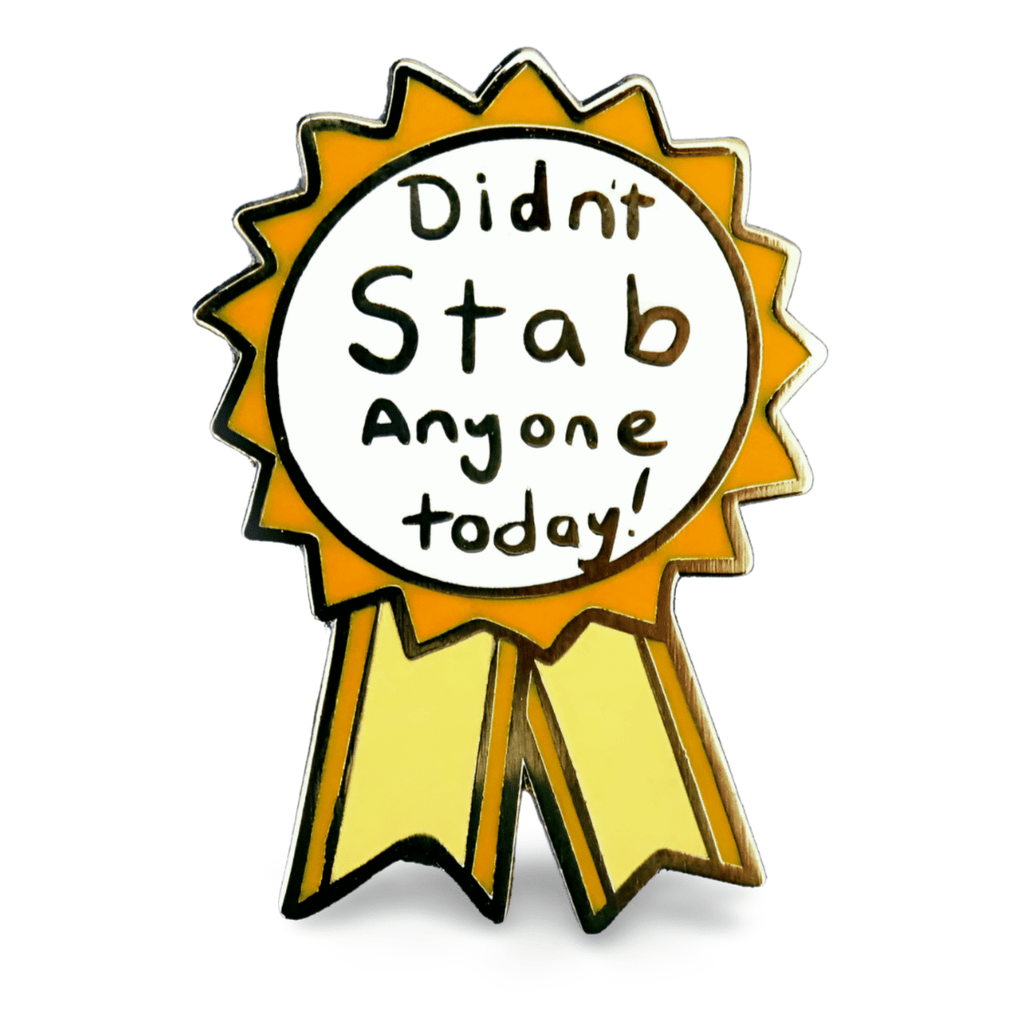 A hard enamel lapel pin on a white background. The pin is in the shape of an award ribbon. The ribbon is yellow and white, and reads Didn’t Stab Anyone Today!