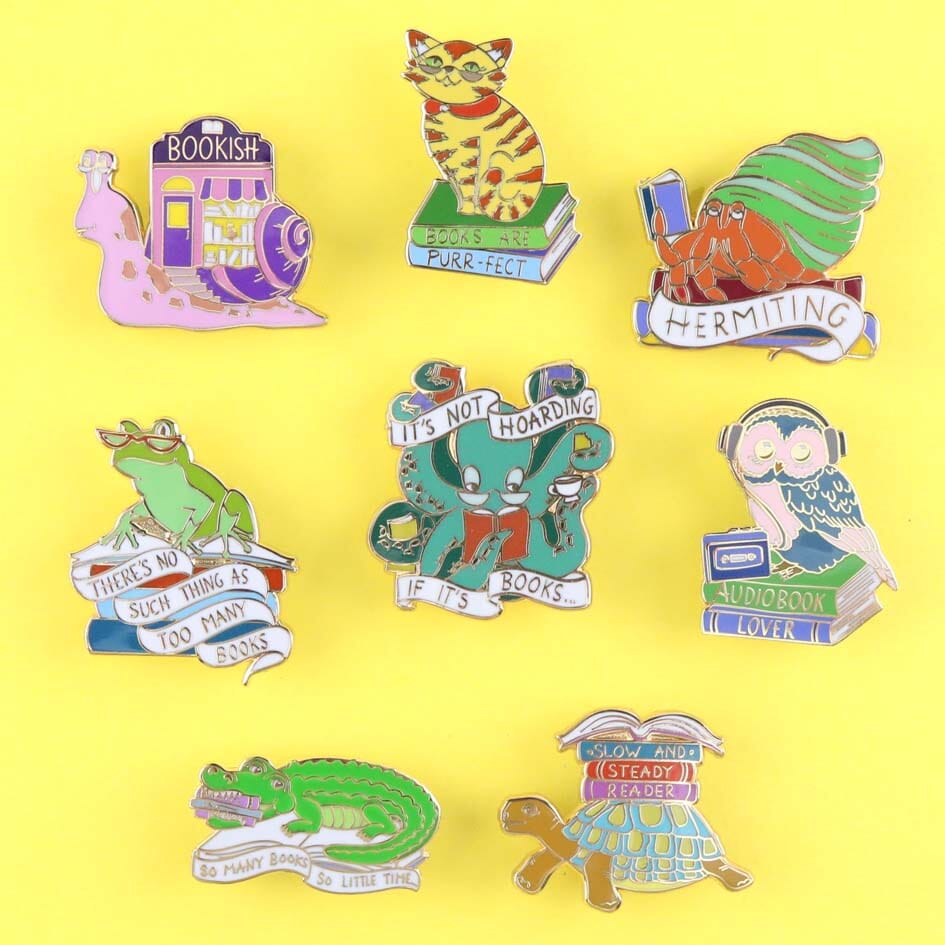A grouping of the Bookish Beasts collection of hard enamel lapel pins.