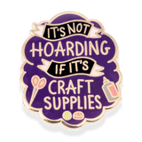 Enamel pin with text 'It's not hoarding if it's craft supplies' on a purple background