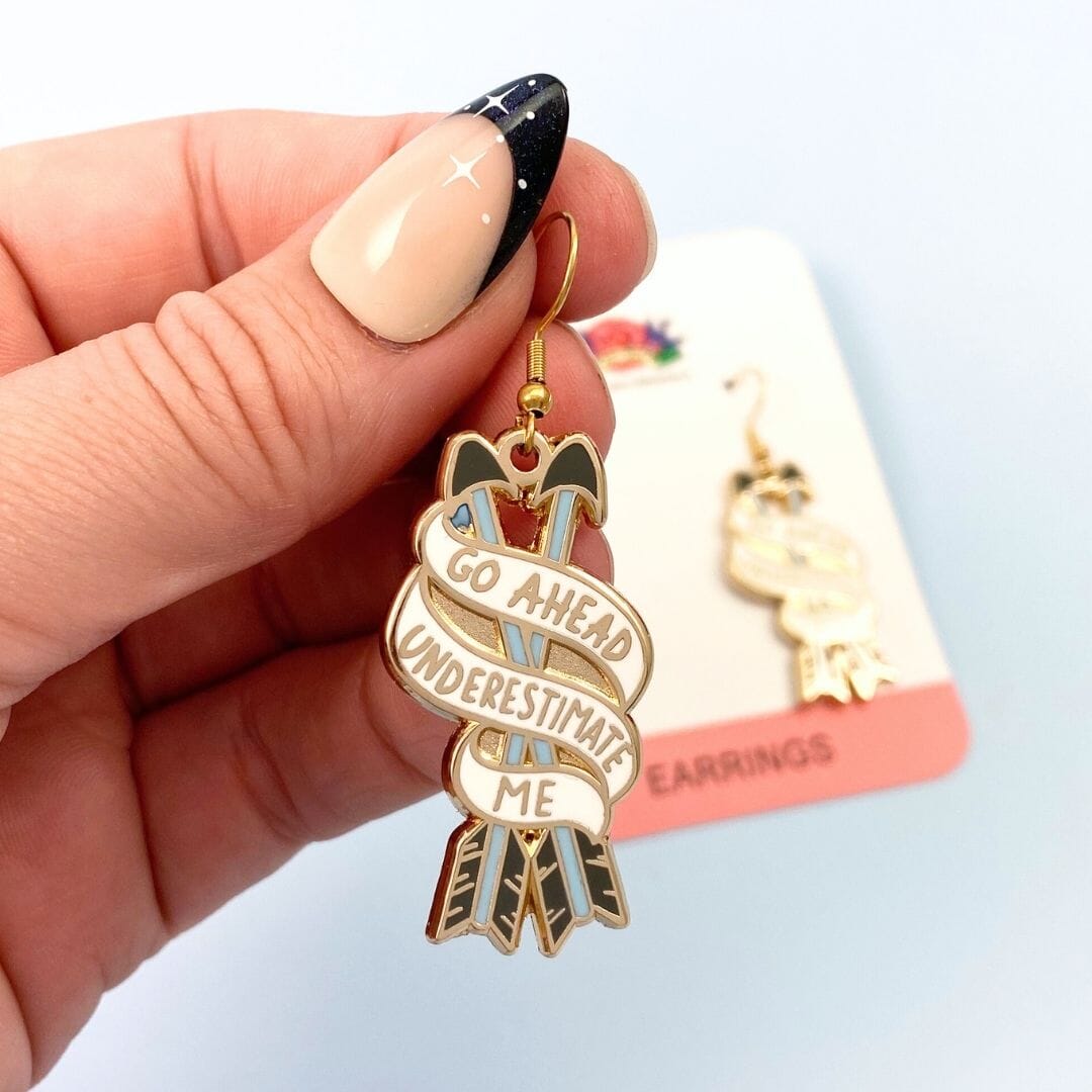 Go ahead underestimate me earrings - one being held, one on bscking card in background