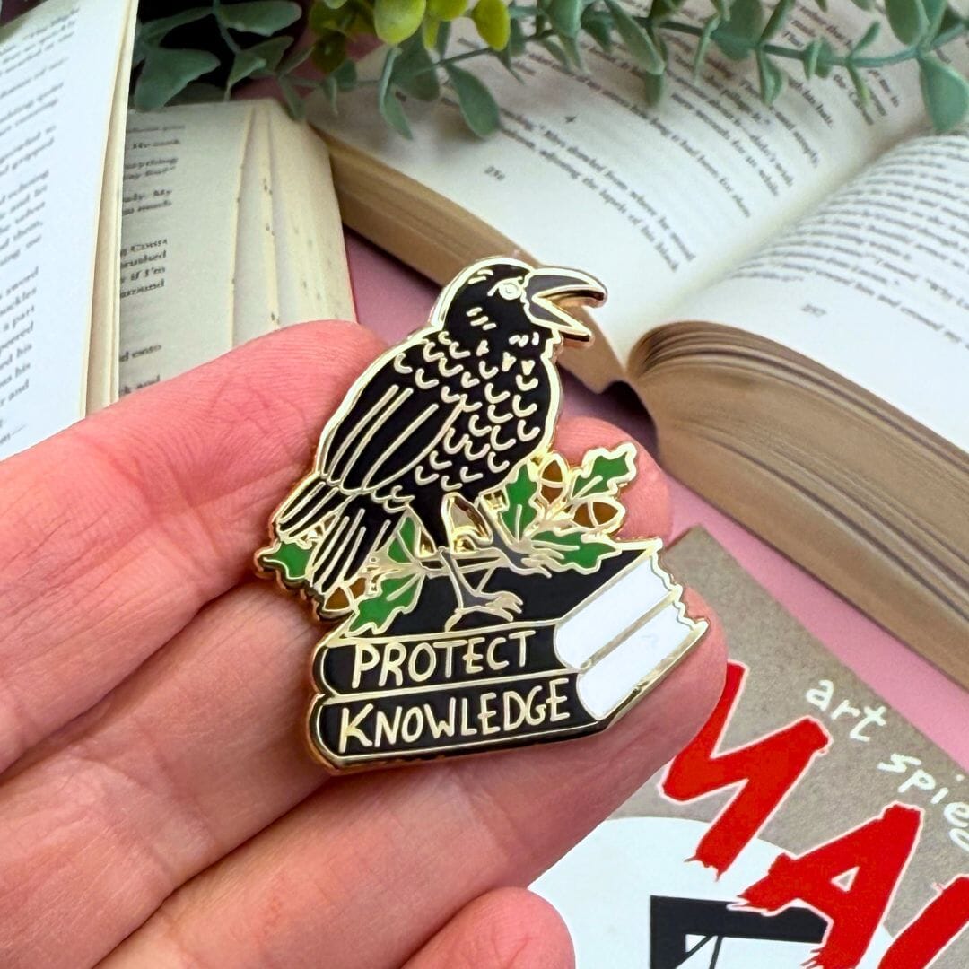 Protect Knowlege pin in hand over books.