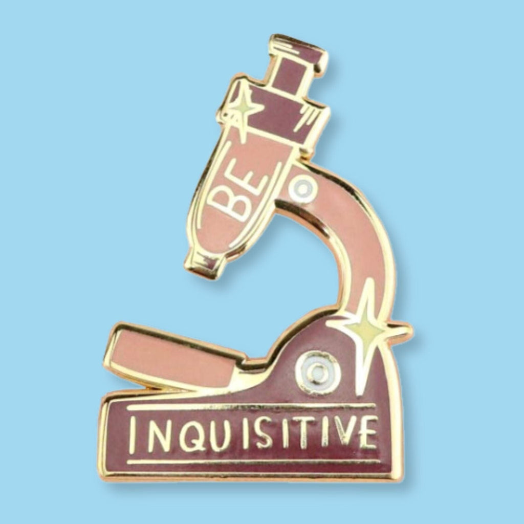 A hard enamel lapel pin on a blue background. The pin is in the shape of a microscope and reads Be Inquisitive.