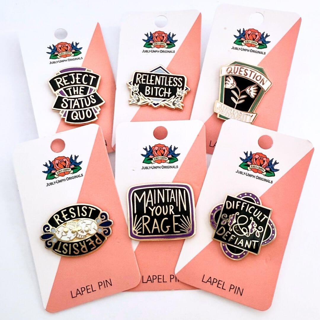 Set of lapel pins with motivational phrases on pink cards.