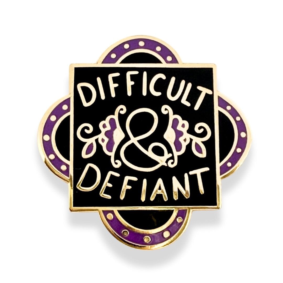 Pin with 'Difficult & Defiant' text on a black background with gold and purple accents