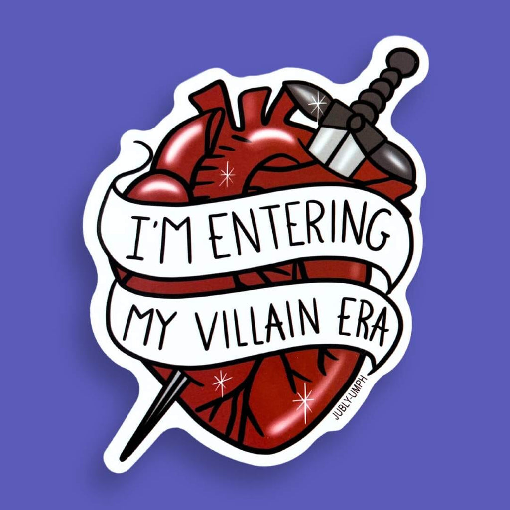 The vinyl sticker is in the shape of a human heart with a dagger on a purple background. The sticker reads I'm Entering My Villain Era.