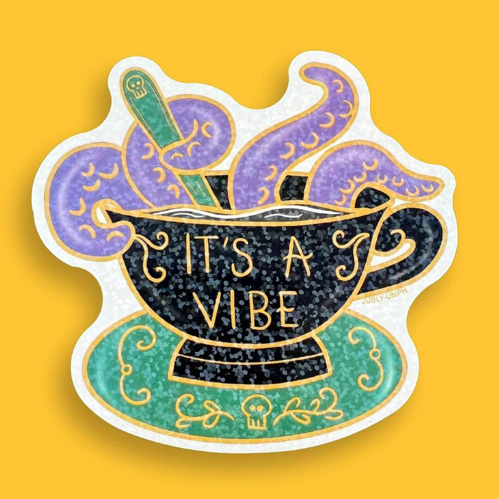 A vinyl sticker displayed on a yellow background. The sticker is in the shape of a black teacup with purple tenticles coming out. The pin reads It's A Vibe.
