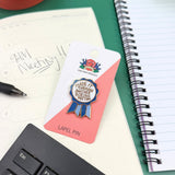 Lapel pin on a card with a notebook, pen, and keyboard in the background