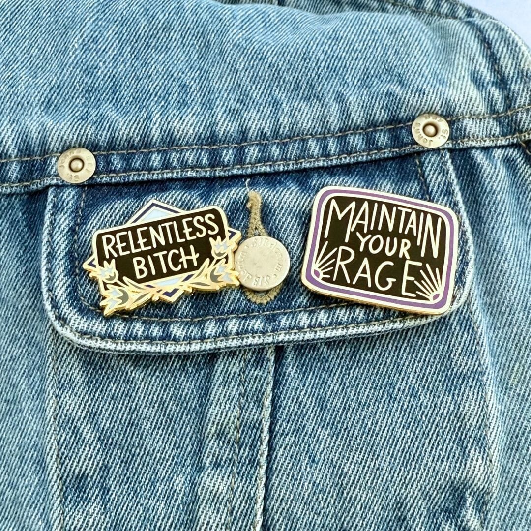 Two pins on a denim jacket, one reading 'Relentless Bitch' and the other 'Maintain Your Rage'.