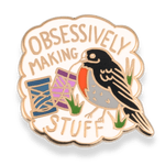 Enamel pin with a bird design and text 'Obsessively Making Stuff' on a white background