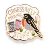 Enamel pin with a bird design and text 'Obsessively Making Stuff' on a white background