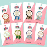 Set of eight lapel pins on pink cards with colorful ribbons and text, against a light blue background.