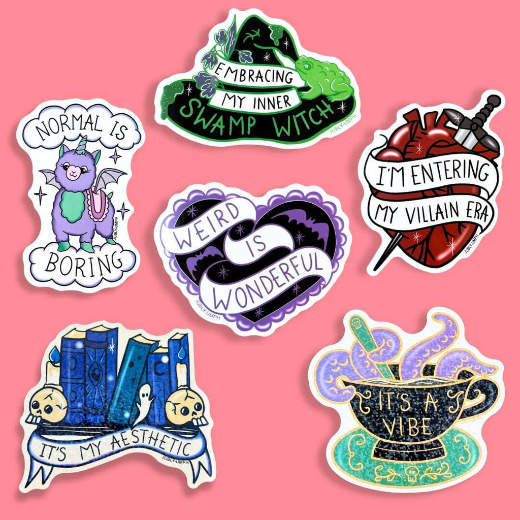 A group of stickers against a pink background. They read Embracing My Inner Swamp Witch, Normal Is Boring, I'm Entering My Villian Era, Weird Is Wonderful, It's My Aesthetic, It's A Vibe.