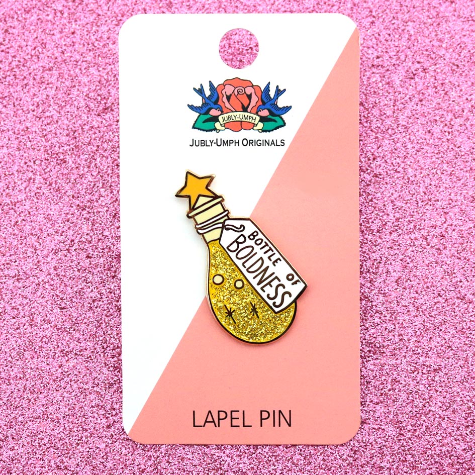 A hard enamel lapel pin on Jubly-Umph cardstock. The pin is in the profile of a bottle with yellow glitter. The pin says Bottle of Boldness.