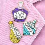Three hard enamel pins are displayed on a pink jacket. The first pin says Bottle of Boldness, The Second pin says Elixir of Courage and the Third pin says Brew of Bravery.