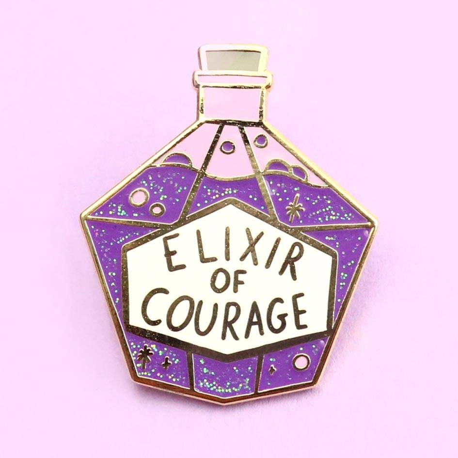 A hard enamel pin on a purple background. The pin is in the shape of a bottle with purple glitter. The pin reads Elixir Of Courage.