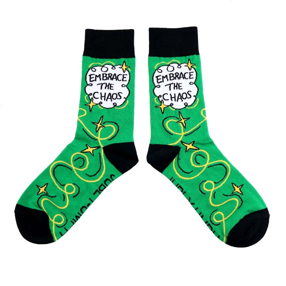 A pair of socks standing against a white background. The socks are green and gold and read Embrace The Chaos. 