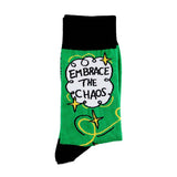 A pair of socks standing against a white background. The socks are green and gold and read Embrace The Chaos. 