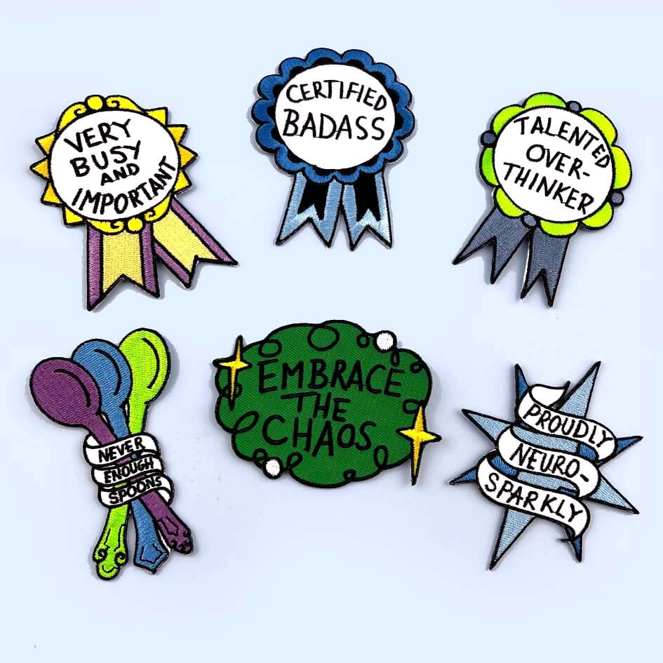 A group of 6 different patches are displayed on a blue background. They read Certified Badass, Talented Over Thinker,Very Busy and Important, Proudly Neuro Sparkly, Never Enough Spoons and Embrace the Chaos.