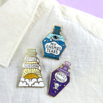 Three hard enamel pins are displayed on a white linen shirt. The first pin says Bottled Sunshine, The Second pin says My Enemies Tears and the Third pin says Mostly Harmless.