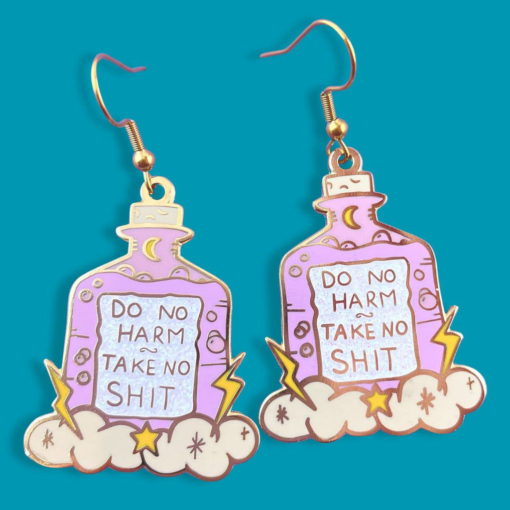 A pair of dangle earrings displayed on a blue background. The earrings are purple and in the shape of a bottle with clouds and lightning bolts. The earrings read Do No Harm Take No Shit.
