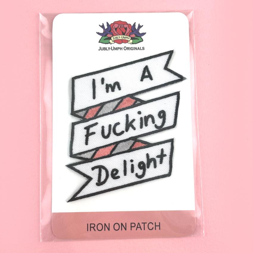 An iron on embroidered patch is being displayed on Jubly-Umph card stock. The patch reads I'm A Fucking Delight.